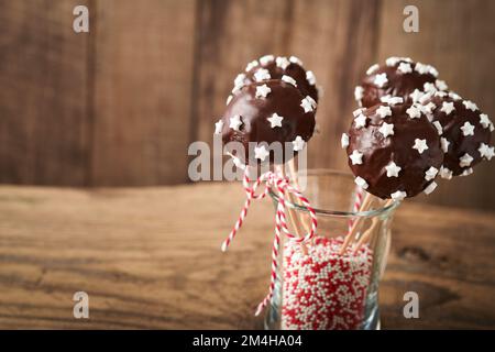 Heirate Weihnachten, süße Kuchenpopps. Weihnachtsdessert runde Brownie-Kuchen mit Sternen auf dunkelgrünem Hintergrund. Weihnachtsessen Dessertkonzept Stockfoto