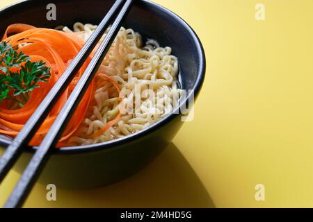 Vegetarische Ramen-Nudeln mit Stäbchen auf gelbem Hintergrund Stockfoto