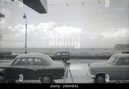 1950er, historische Autos der Epoche, die an der Strandpromenade in Morecambe, einer traditionellen Küstenstadt in Lancashire, England, geparkt sind. Stockfoto