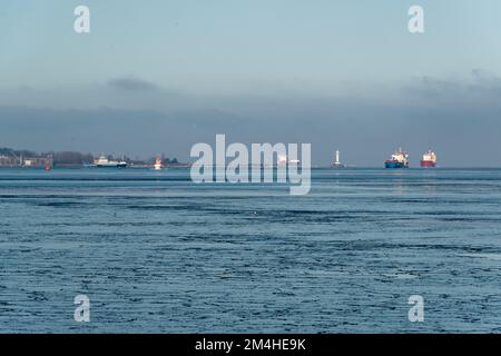 Gefrorenes Wasser in der Kieler Förde an einem Sonnigen kalten Wintertag Frachtschiffe fahren zur Schleuse des Nord-Ostsee-Kanals Stockfoto