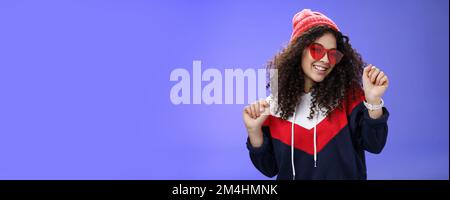 Stilvolle und feminine Freundin tanzen Spaß haben das Gefühl optimistisch wie das Wetter fühlen sich warm und gemütlich in stilvollen roten Beanie und Sonnenbrillen tanzen Stockfoto