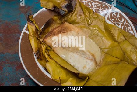 Gefülltes Tamale auf Holztisch serviert, gefülltes Tamale auf Bananenblatt auf Holztisch serviert, typisch nicaragua Essen Stockfoto