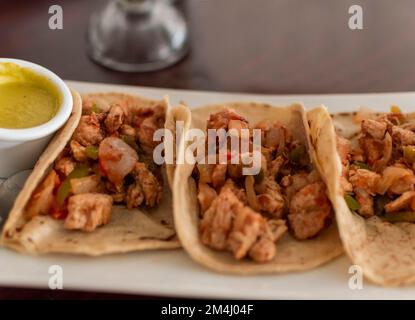 Mexikanische Tacos al Pastor serviert mit heißer Sauce, köstliche mexikanische Hühnchen-Tacos mit Salsa und Pico de gallo serviert auf dem Tisch, Blick auf Hühnchen Stockfoto