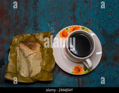 Gefüllte Tamale mit einer Tasse Kaffee auf einem Holztisch, traditionelle gefüllte Pisque Tamal neben einer Tasse Kaffee auf einem Holztisch, Central Stockfoto