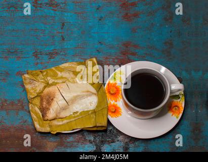 Traditionelles gefülltes Pisque Tamal mit einer Tasse Kaffee auf einem Holztisch, typisch zentralamerikanisches Essen gefüllt mit Tamal Pisque, gefüllte Tamale mit Stockfoto