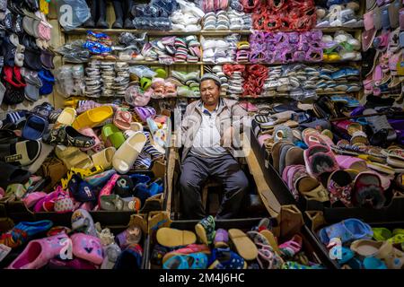 Schuhverkäufer in seinem Stand, sehr viele Schuhe, Osh Bazaar, Kirgisistan, Zentralasien Stockfoto