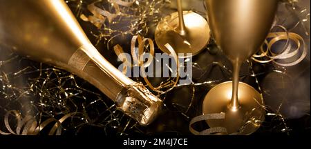 Silvester. Luxuriöse goldene Champagnerflasche mit Gläsern und goldenen Bändern auf schwarzem Hintergrund. Banner Stockfoto