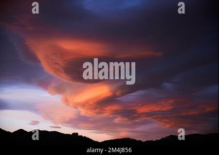 Sonnenaufgang mit einem Himmel voller wunderschöner Wolken mit Blau- und Orangenfarben, die einen Wirbel bilden Stockfoto