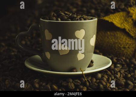 Eine Tasse Kaffee über Kaffeebohnen in einem Leinenbeutel Stockfoto