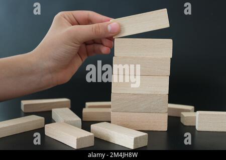 Männerhand sortiert Holzblöcke auf schwarzem Hintergrund Stockfoto