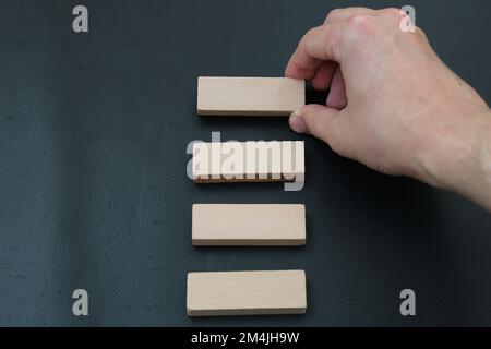 Männerhand sortiert Holzblöcke auf schwarzem Hintergrund Stockfoto