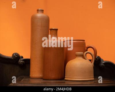 Nahaufnahme von Tongefässen. Flaschen und Kannen. Orangefarbene Wand. Stockfoto