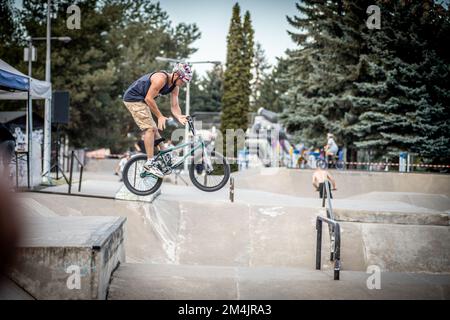 Ein junger Mann, der während des BMX-Rennens im Skate Park in Kosice auf ein Fahrrad springt Stockfoto