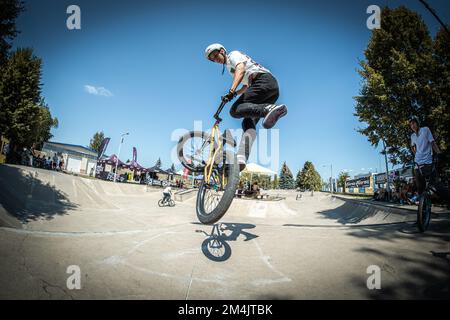 Ein junger Mann, der während des BMX-Rennens im Skate Park in Kosice auf ein Fahrrad springt Stockfoto