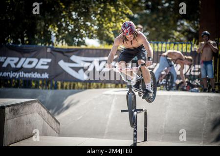 Ein junger Mann, der während des BMX-Rennens im Skate Park in Kosice auf ein Fahrrad springt Stockfoto