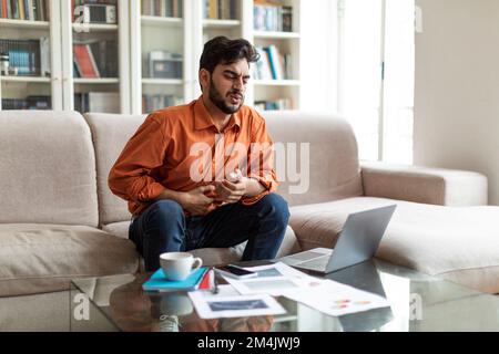 Ein arabischer Freiberufler, der Magenschmerzen hat, den Bauch berührt Stockfoto