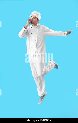Der junge Koch springt auf blauem Hintergrund Stockfoto