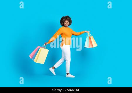Eine sorgenfreie schwarze Frau, die mit Einkäufen herumläuft Stockfoto