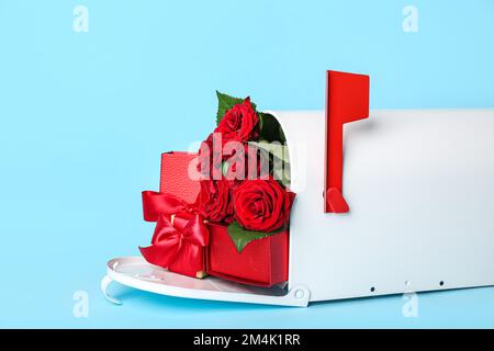 Briefkasten mit Geschenken und Rosen auf blauem Hintergrund. Valentinstag-Feier Stockfoto