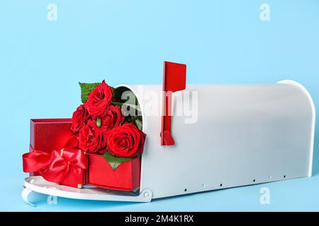 Briefkasten mit Geschenken und Rosen auf blauem Hintergrund. Valentinstag-Feier Stockfoto