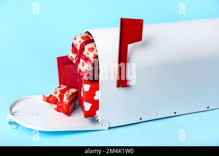 Briefkasten mit Geschenken und Umschlägen auf blauem Hintergrund. Valentinstag-Feier Stockfoto