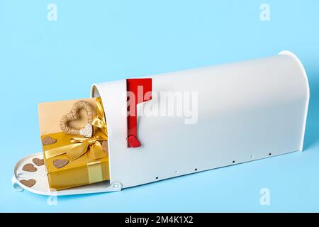 Briefkasten mit Geschenken, Umschlag und Herzen auf blauem Hintergrund. Valentinstag-Feier Stockfoto