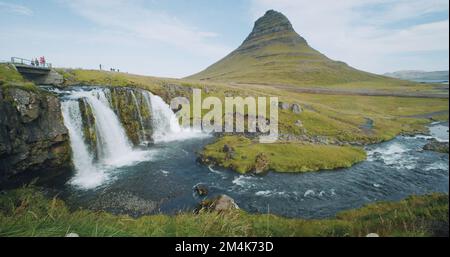 Kirkjufellsfoss und Kirkjufell in Nordisland sind nicht anerkannte Touristen auf der Brücke Stockfoto