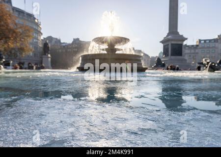 Der Brunnen am Trafalgar Square bleibt bis zum Morgen gefroren. Die Leute haben Spaß mit Eisstücken auf dem Brunnen. Aufnahme am 16. Dezember 2022. ©B Stockfoto