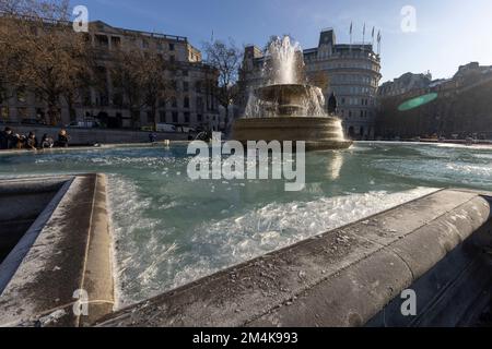 Der Brunnen am Trafalgar Square bleibt bis zum Morgen gefroren. Die Leute haben Spaß mit Eisstücken auf dem Brunnen. Aufnahme am 16. Dezember 2022. ©B Stockfoto