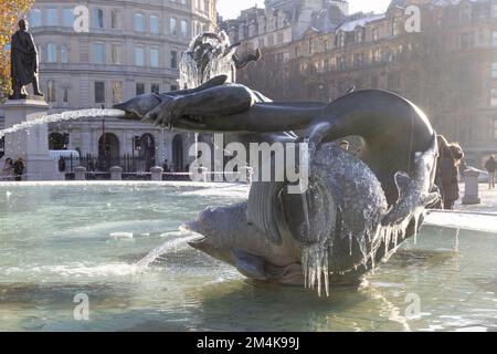 Der Brunnen am Trafalgar Square bleibt bis zum Morgen gefroren. Die Leute haben Spaß mit Eisstücken auf dem Brunnen. Aufnahme am 16. Dezember 2022. ©B Stockfoto