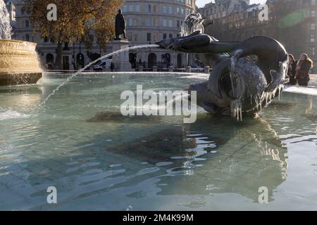 Der Brunnen am Trafalgar Square bleibt bis zum Morgen gefroren. Die Leute haben Spaß mit Eisstücken auf dem Brunnen. Aufnahme am 16. Dezember 2022. ©B Stockfoto