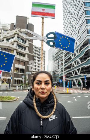 Den Haag, Niederlande, 21/12/2022, Eine Demonstrantin während der heutigen Demonstration in Den Haag, die das iranische Regime anprangert; mit einer Schlinge um den Hals und in der Erwartung, dass die Europäische Union sie freischneidet. Eine nicht allzu große, aber sehr lautstarke Gruppe iranischer Anhänger hat heute Nachmittag einen lauten Protest inszeniert und das niederländische Repräsentantenhaus aufgefordert, die iranische Botschaft in den Niederlanden zu schließen und ihre Diplomaten auszuweisen. Vor einigen Wochen brachen im Iran Massendemonstrationen aus, nachdem die Sicherheitskräfte hart gegen Demonstranten vorgegangen waren. Von den Verhaftungen waren zwei für den plötzlichen Tod von 22 verantwortlich Stockfoto