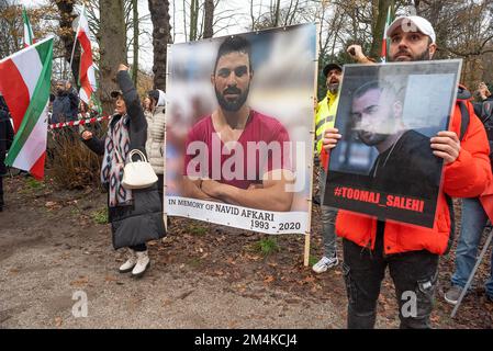 Den Haag, Niederlande, 21/12/2022, Eine Gruppe männlicher und weiblicher Demonstranten, während der heutigen Demonstration in Den Haag, in der das iranische Regime angeprangert wird; Mit Flaggen und Porträts von Opfern im Iran Hat Eine nicht zu große, aber sehr lautstarke Gruppe iranischer Anhänger, die heute Nachmittag einen lautstarken Protest inszeniert hat, das niederländische Repräsentantenhaus aufgefordert, die iranische Botschaft in den Niederlanden zu schließen und ihre Diplomaten auszuweisen. Vor einigen Wochen brachen im Iran Massendemonstrationen aus, nachdem die Sicherheitskräfte hart gegen Demonstranten vorgegangen waren. Von den Verhaftungen waren zwei für den plötzlichen Tod des 22-jährigen Mahsa verantwortlich Stockfoto