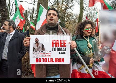 Den Haag, Niederlande, 21/12/2022, Eine Gruppe männlicher und weiblicher Demonstranten, während der heutigen Demonstration in Den Haag, bei der das iranische Regime angeprangert wird; mit Flaggen und einem Poster eines Opfers im Iran. Eine nicht allzu große, aber sehr lautstarke Gruppe iranischer Anhänger hat heute Nachmittag einen lauten Protest inszeniert und das niederländische Repräsentantenhaus aufgefordert, die iranische Botschaft in den Niederlanden zu schließen und ihre Diplomaten auszuweisen. Vor einigen Wochen brachen im Iran Massendemonstrationen aus, nachdem die Sicherheitskräfte hart gegen Demonstranten vorgegangen waren. Von den Verhaftungen waren zwei für den plötzlichen Tod des 22-jährigen Mahs verantwortlich Stockfoto