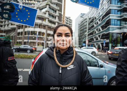 Den Haag, Niederlande, 21/12/2022, Eine Demonstrantin während der heutigen Demonstration in Den Haag, die das iranische Regime anprangert; mit einer Schlinge um den Hals und in der Erwartung, dass die Europäische Union sie freischneidet. Eine nicht allzu große, aber sehr lautstarke Gruppe iranischer Anhänger hat heute Nachmittag einen lauten Protest inszeniert und das niederländische Repräsentantenhaus aufgefordert, die iranische Botschaft in den Niederlanden zu schließen und ihre Diplomaten auszuweisen. Vor einigen Wochen brachen im Iran Massendemonstrationen aus, nachdem die Sicherheitskräfte hart gegen Demonstranten vorgegangen waren. Von den Verhaftungen waren zwei für den plötzlichen Tod von 22 verantwortlich Stockfoto