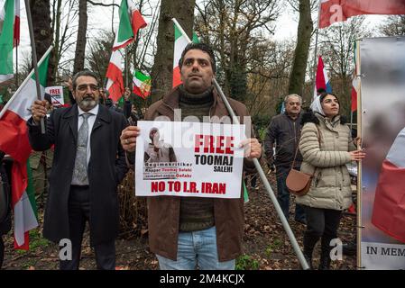 Den Haag, Niederlande, 21/12/2022, Eine Gruppe männlicher und weiblicher Demonstranten, während der heutigen Demonstration in Den Haag, bei der das iranische Regime angeprangert wird; mit Flaggen und einem Poster eines Opfers im Iran. Eine nicht allzu große, aber sehr lautstarke Gruppe iranischer Anhänger hat heute Nachmittag einen lauten Protest inszeniert und das niederländische Repräsentantenhaus aufgefordert, die iranische Botschaft in den Niederlanden zu schließen und ihre Diplomaten auszuweisen. Vor einigen Wochen brachen im Iran Massendemonstrationen aus, nachdem die Sicherheitskräfte hart gegen Demonstranten vorgegangen waren. Von den Verhaftungen waren zwei für den plötzlichen Tod des 22-jährigen Mahs verantwortlich Stockfoto