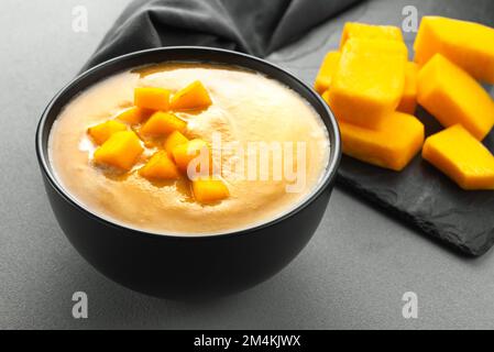 Vegetarische Kürbissuppe im Herbst in einer schwarzen Schüssel. Kürbissuppe Stockfoto