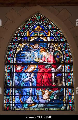 Die Krönung der Jungfrau Maria durch Gott nach ihrer Himmelsannahme, dargestellt in einem Buntglasfenster. Fotografiert in einer bemalten Kirche, St. Marys C. Stockfoto