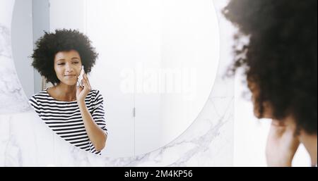 Nur ein Wischen hier und ich bin fertig. Eine selbstbewusste junge Frau wischte sich das Gesicht mit einem Reinigungsmittel, während sie zu Hause in einen Spiegel im Badezimmer schaute Stockfoto