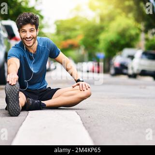 Starten Sie das Rennen um einen besseren Lebensstil. Porträt eines sportlichen jungen Mannes, der sich beim Sport im Freien die Beine streckt. Stockfoto