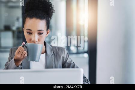 Kaffee ist ein großartiger Ansporn, um die Produktivität in Gang zu bringen. Eine attraktive junge Geschäftsfrau, die eine Tasse Kaffee in ihrem Büro trinkt. Stockfoto