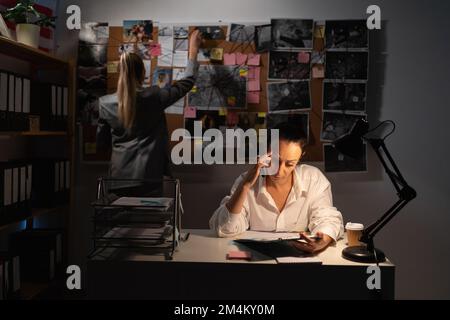Kollegen Detektive, die im Büro arbeiten und ein Verbrechen untersuchen, sehen sich die Beweisaufnahme an. Speicherplatz kopieren Stockfoto