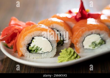 Sushi-Brötchen Philadelphia mit Lachs und Frischkäse auf einem Teller mit Ingwer und Wasabi. Sushi-Menü. Japanisches Speisekonzept Stockfoto