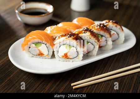 Sushi-Brötchen mit Lachs, Aal, Thunfisch, Avocado, königlicher Garnele, Frischkäse, Kaviar Tobiko, chuka. Sushi-Menü. Japanisches Essen. Speicherplatz kopieren Stockfoto