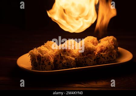 Das Sushi mit einer Fackel in der Sushi-Bar anzünden. Japanisches Speisekonzept. Speicherplatz kopieren Stockfoto