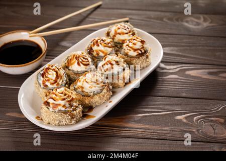 Heiß gebratene Sushi-Brötchen mit Aal, Kalbskaviar und Käse. Sushi-Menü. Japanisches Essen. Heiße gebratene Sushi-Brötchen. Speicherplatz kopieren Stockfoto