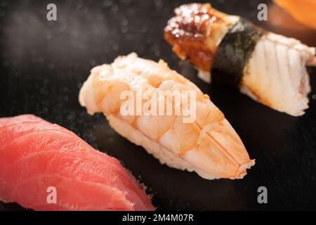 Sashimi-Sushi auf schwarzem Hintergrund, Meeresfrüchte-Delikatessen Nigiri-Sushi auf schwarzem Hintergrund. Sushi mit Aal, Lachs und Thunfisch, Restaurantmenü Stockfoto