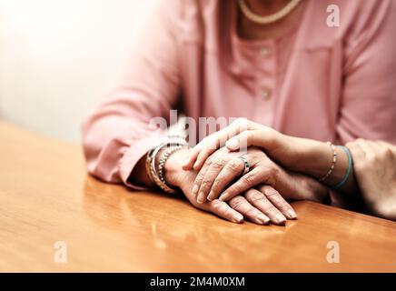 Du musst dir keine Sorgen machen. Eine Krankenschwester, die eine ältere Frau behaglich an den Händen hält. Stockfoto