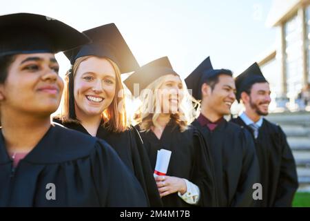 Dieser Moment hat lange auf sich warten lassen. Eine Gruppe von Schülern, die am Tag der Abschlussfeier in einer Schlange stehen. Stockfoto