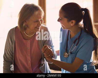 Ich bin hier, um Ihnen bei jedem Schritt zu helfen. Ein Betreuer, der einem älteren Patienten in einem Pflegeheim hilft. Stockfoto